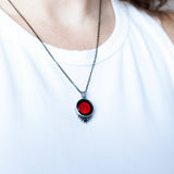 model wearing red moon classic necklace with black crystal, chest close-up